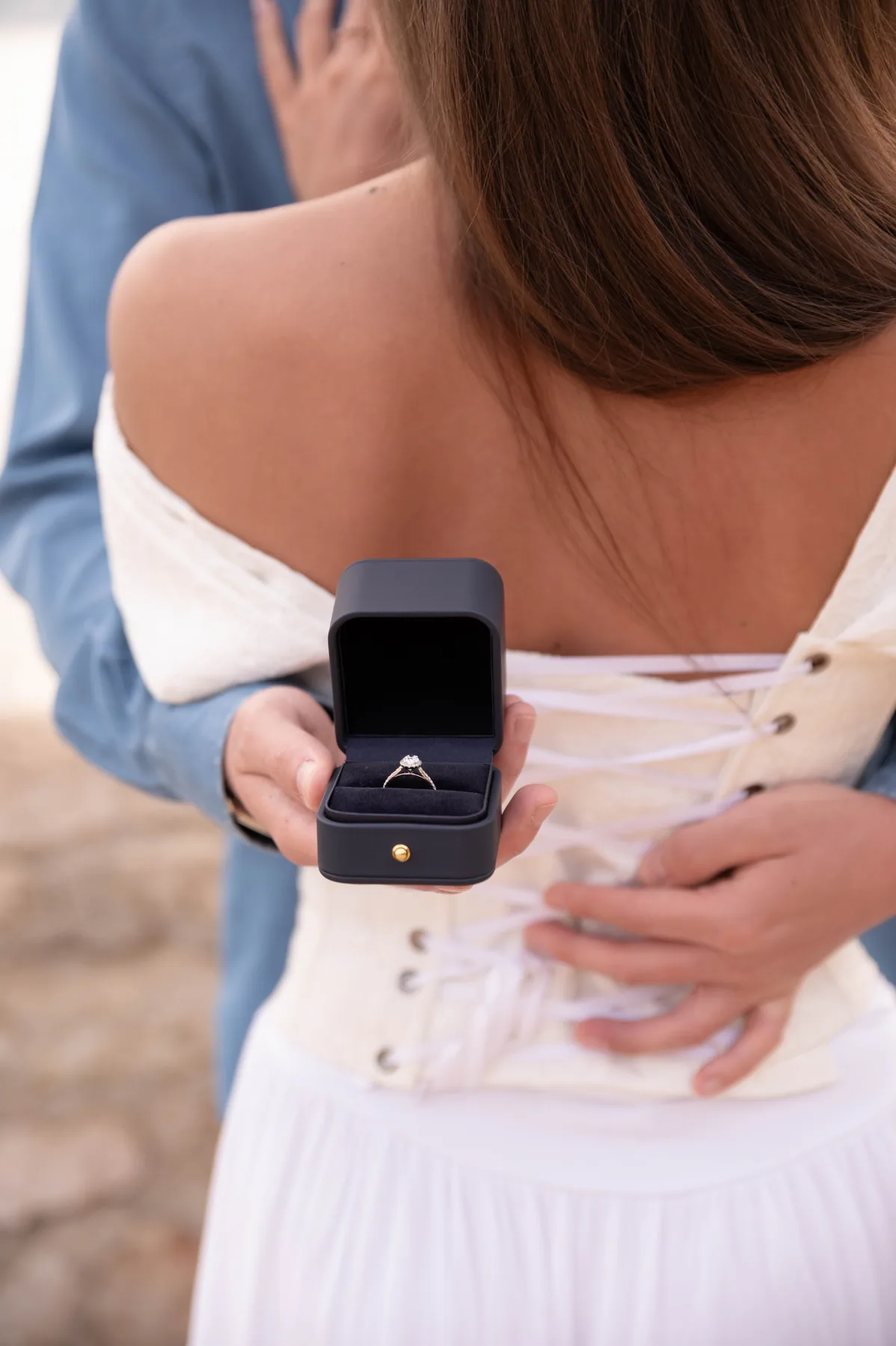 Opening the ring box behind her back