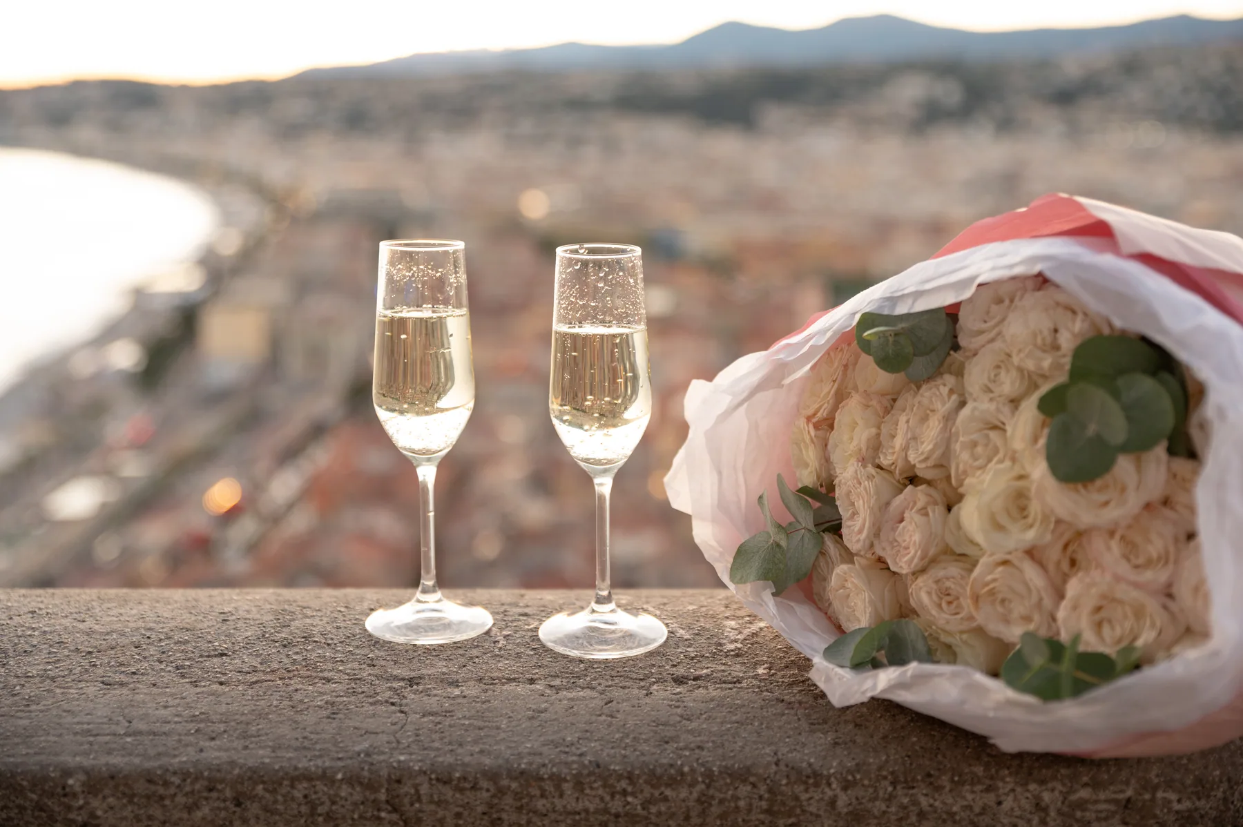 Champagne and a bouquet above the bay at sunset